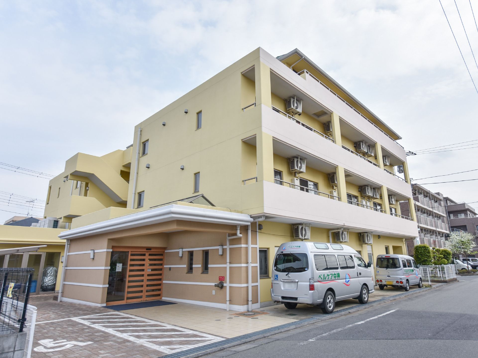 建物は、全体的にベージュ系の色となっている。エントランスの扉はガラスだけではなく、一部に木を使い、温かい印象となっている。