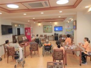 イスに腰かけたスタッフと入居者たちが軽食をとっている。
