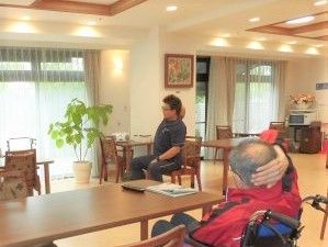 リハビリスタッフが入居者に機能訓練の運動を指導している。