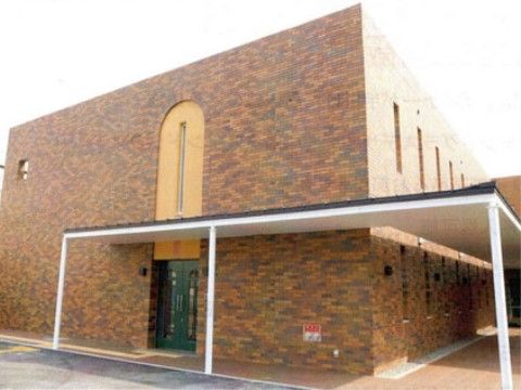 施設は２階建てのコンパクトな外観となっており、落ち着いた色合いをしている。前方には開けた空間があり、通行の妨げとなる物体は取り除かれている。