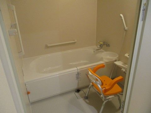 浴槽付近の壁には、手すりやつかまり用の棒が取り付けられている。また、シャワー台の手前には、入浴時における介護用の椅子が用意されている。