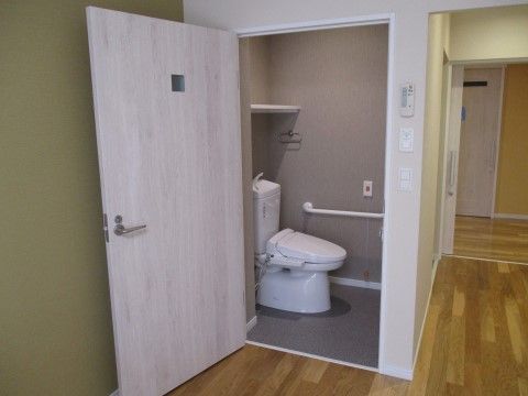 居室とトイレの間には段差がない。トイレの壁には手すりが取り付けられているほか、施設のスタッフを呼び出すことのできるボタンがある。