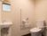 トイレはスペースにゆとりをもたせている。便器の両側にある手すりが立ち座りをサポートしてくれる。万が一に備え呼び出しボタンも設置されている。