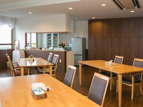 開放感のある空間にブラウンの椅子やテーブルがあり落ち着いた雰囲気である。冷蔵庫やキッチンがあり、食事やお茶をお楽しみいただける。