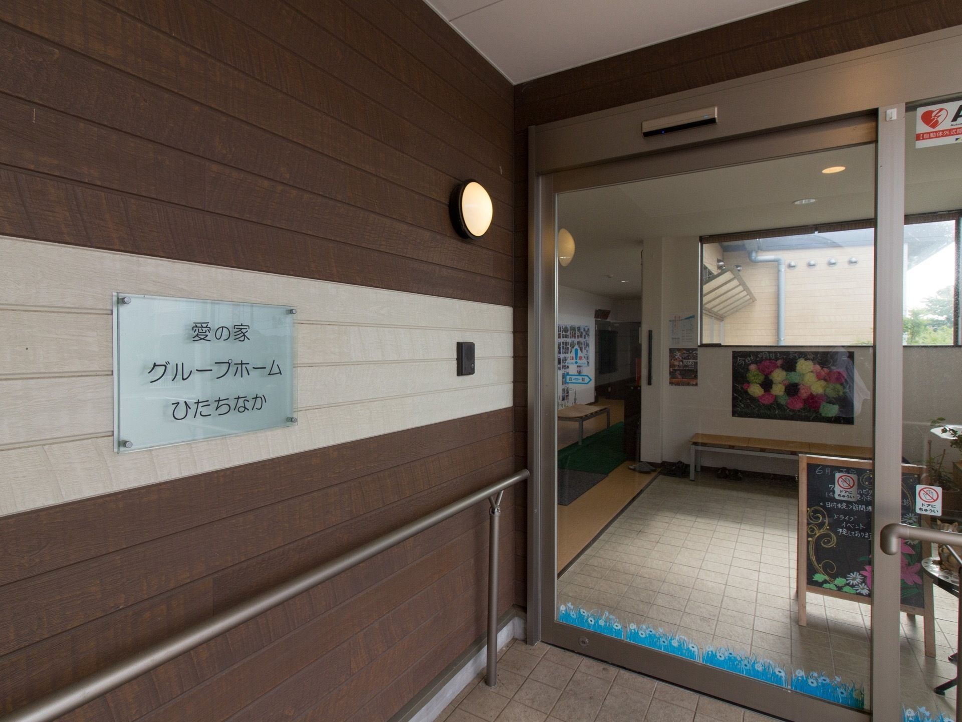 外と中は、透明な自動ドアで仕切られている。ドア付近のブラウン色の壁には、手すりが取り付けられている。