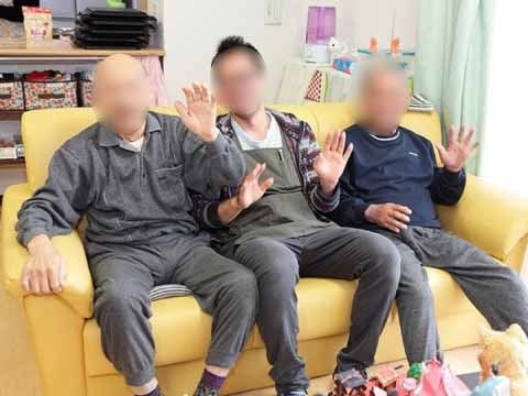 ３人掛けのソファーに座り、カメラに向かって手を振る男性たち