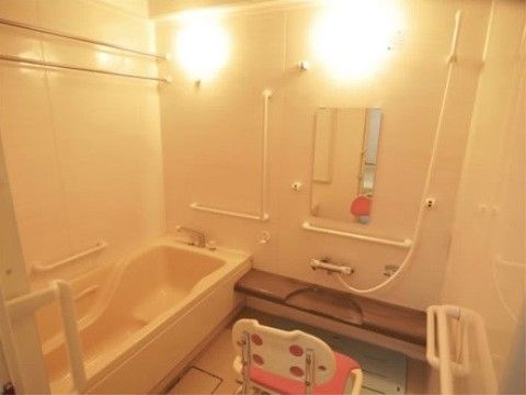 「愛の家グループホーム長岡琴平」の浴室。跨ぎやすい浴槽に、ウレタンクッションが付いたシャワーチェアといった快適な浴室。