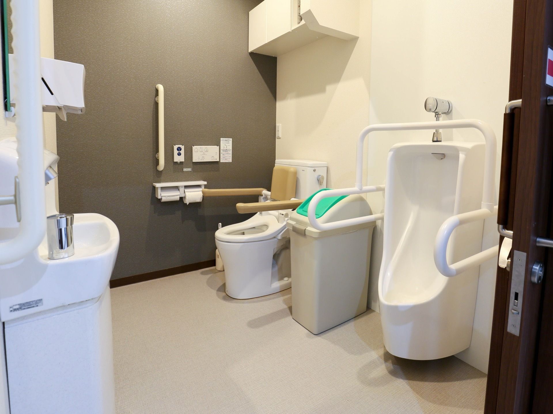男性用の小便器を備えた、トイレである。両サイドには、手すりが備えられている。手洗い場も設置されている。
