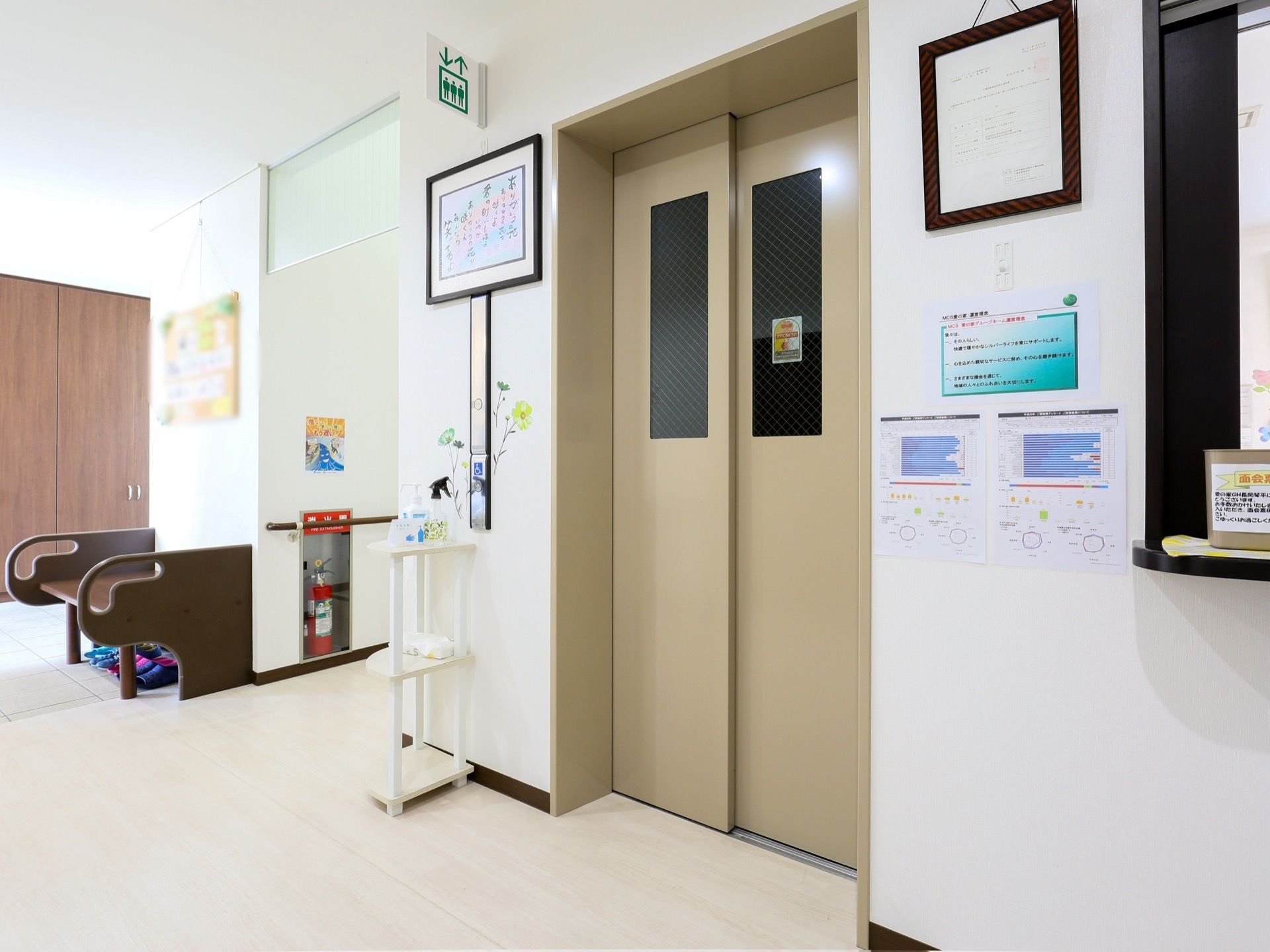 中の様子が見える、窓が設置されたエレベーターである。出入口は広々としている。壁にはさまざまな掲示板が貼られている。