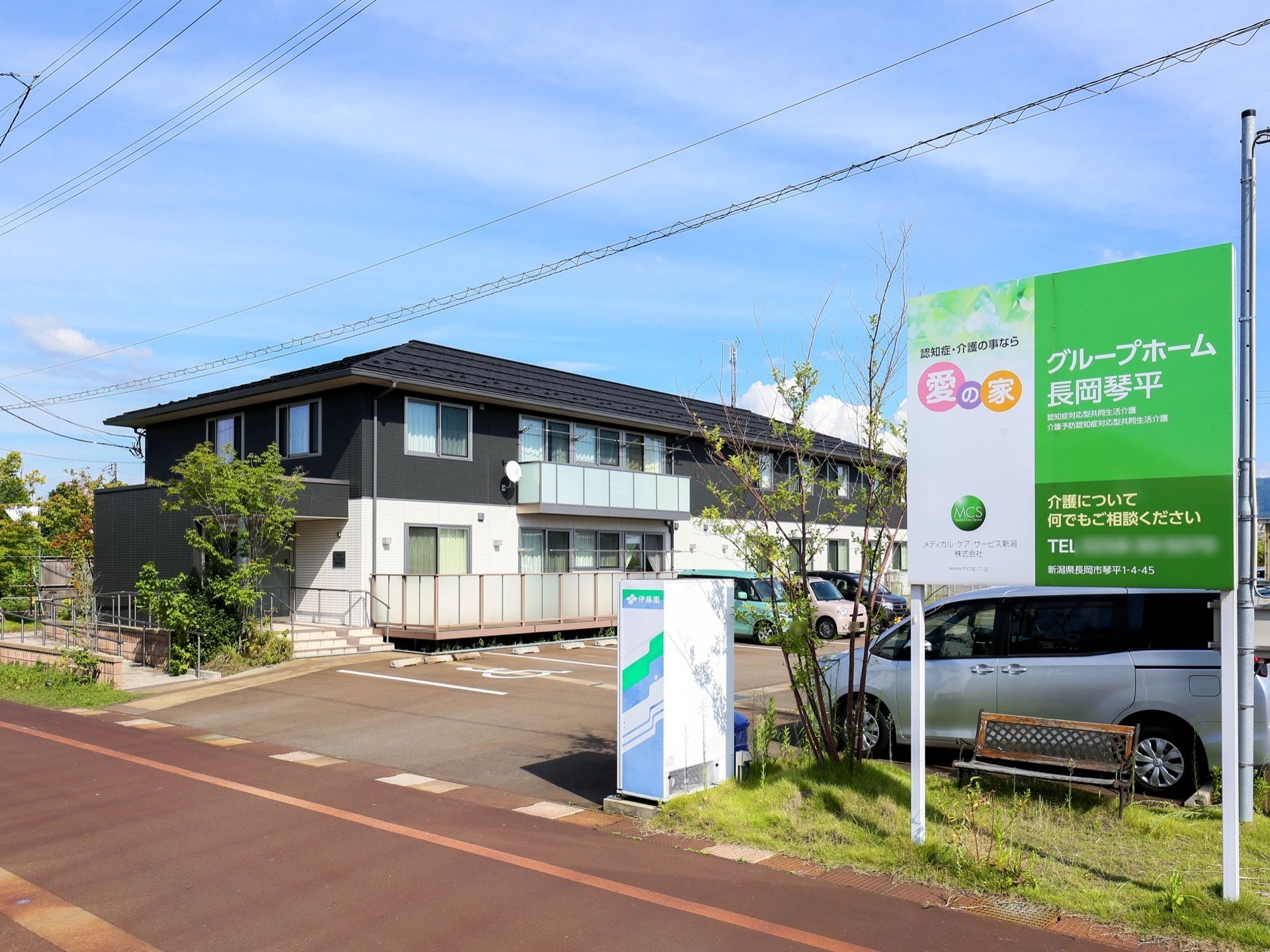 道路に面したところに、白と緑の施設看板がある。そばに自動販売機が備えられている。駐車場も完備。