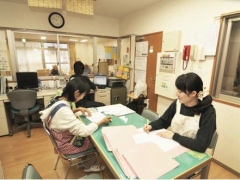 並べた机でスタッフがそれぞれの作業を行う、他の部屋が望める窓がある部屋