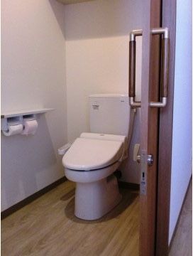 トイレのドアは焦げ茶色である。同色の取っ手にはメタリックな素材を組み合わせている。個室内は木目が活きた板を用いている。