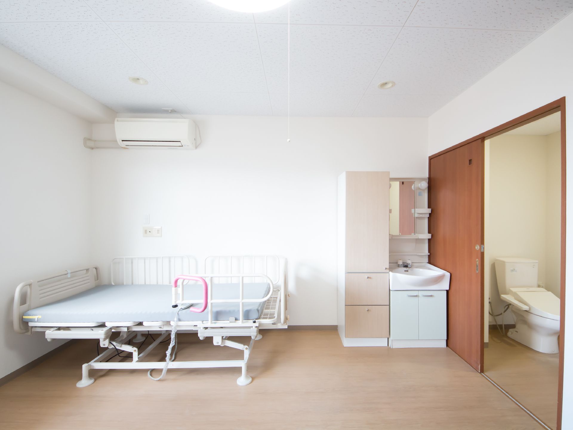 居室にはエアコンと介護用ベッド、収納棚、洗面、照明器具が設置されている。床はフローリングでバリアフリーである。