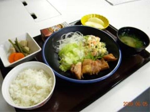 お盆の上に置かれた、野菜を多く使ったおかずとご飯とみそ汁で構成された食事
