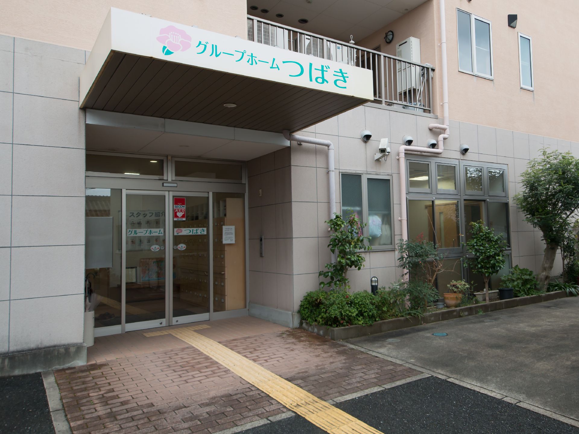広い玄関ポーチと、段差を抑えて点字ブロックを整備した地面を持つ玄関