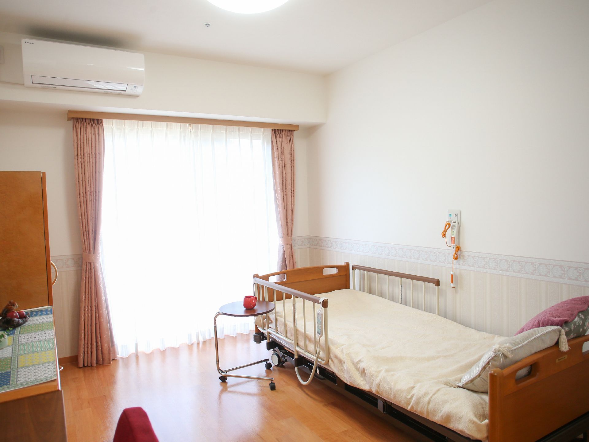 居室の壁クロスは、腰の高さから床にかけてデザイン性のあるものが使われている。備え付けのベッドは電動の介護用である。