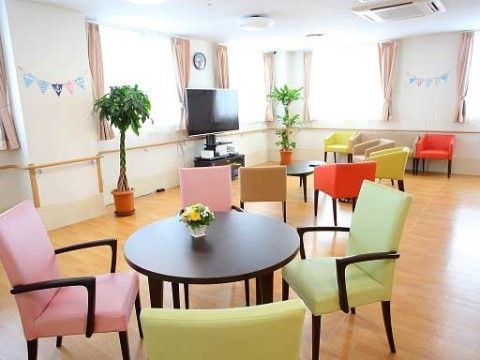 テレビと複数のテーブルと椅子が設置されたリビング