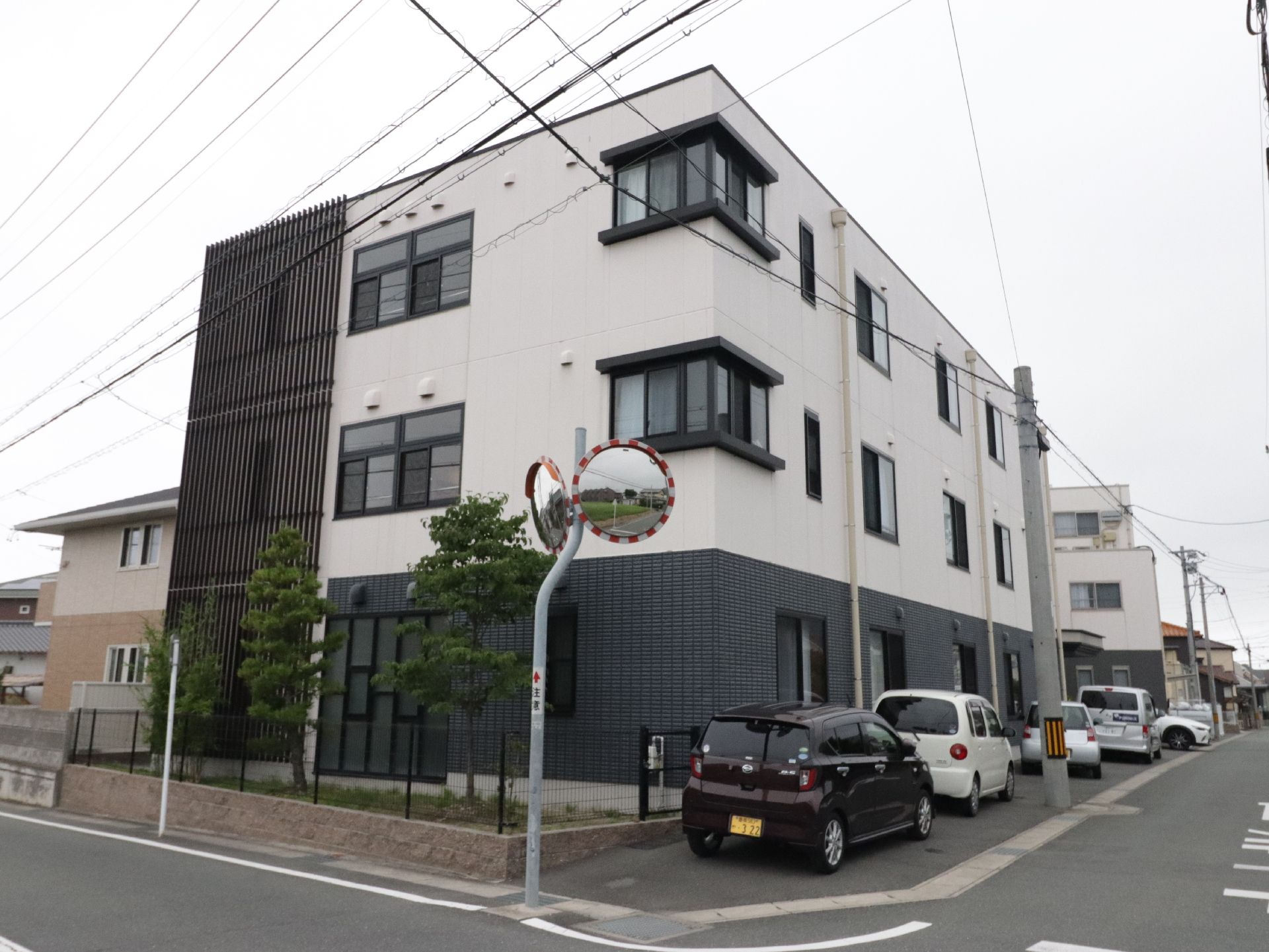 １階部分の壁はダークブラウン、それ以外はアイボリーである。窓がたくさんあり、明るい３階建ての建物である。
