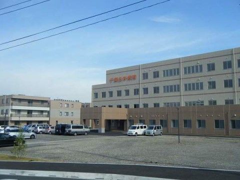 広い駐車場と空き地の奥に建つ、１階部分の間取りが広い建物