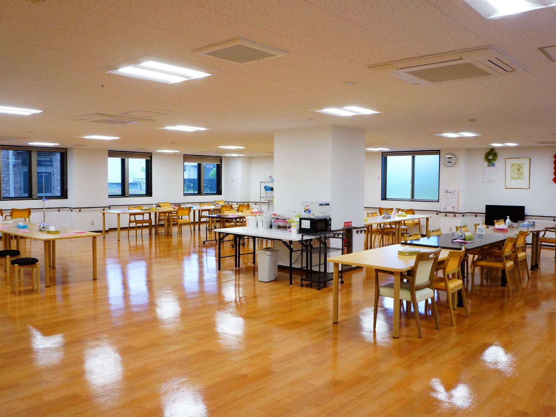 広々とした開放感のある多目的スペースには、机やいすが並べられ、机の上にはティッシュなどの小物が載っている。