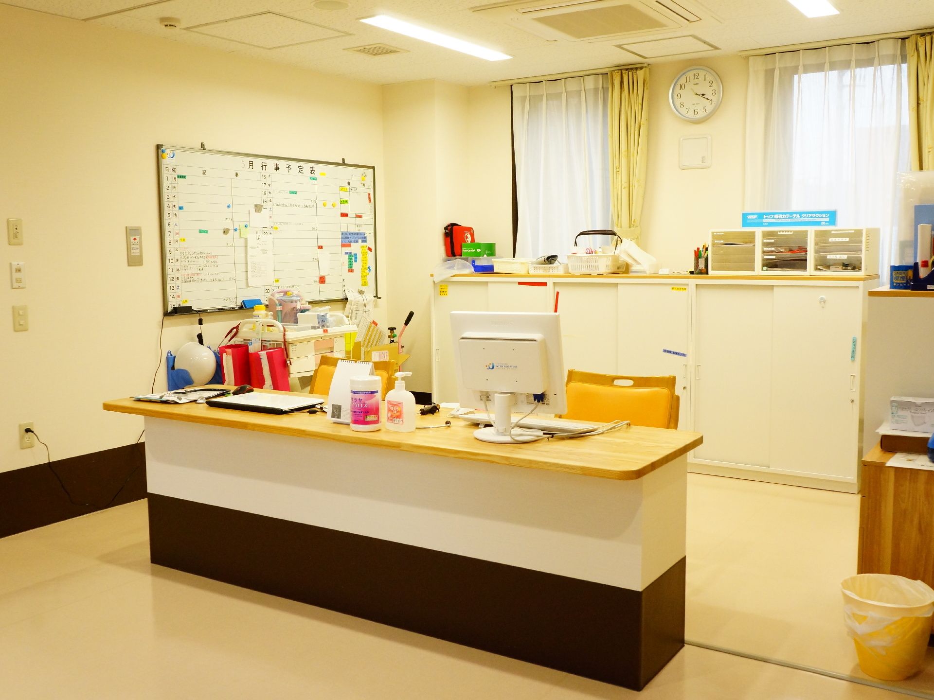 明るい印象の受け付け場所にはパソコンや書類棚、時計などが置かれている。消毒薬も完備し、感染症対策もきちんと行っている。