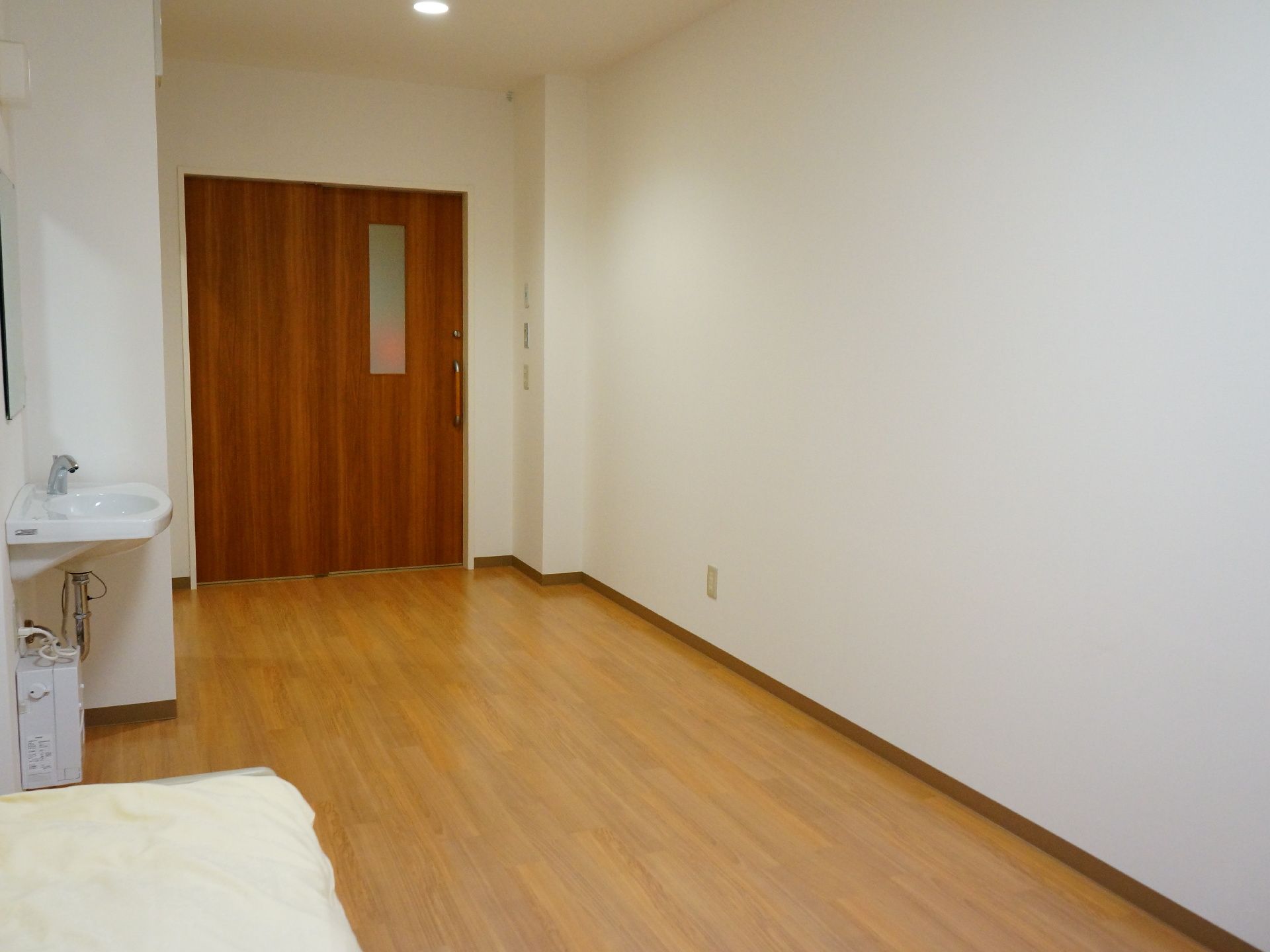 居室の床は落ち着いた色合いの木目調で安らぐことができる。居室のドアは大きめに作られていて車いすの方にも安心。