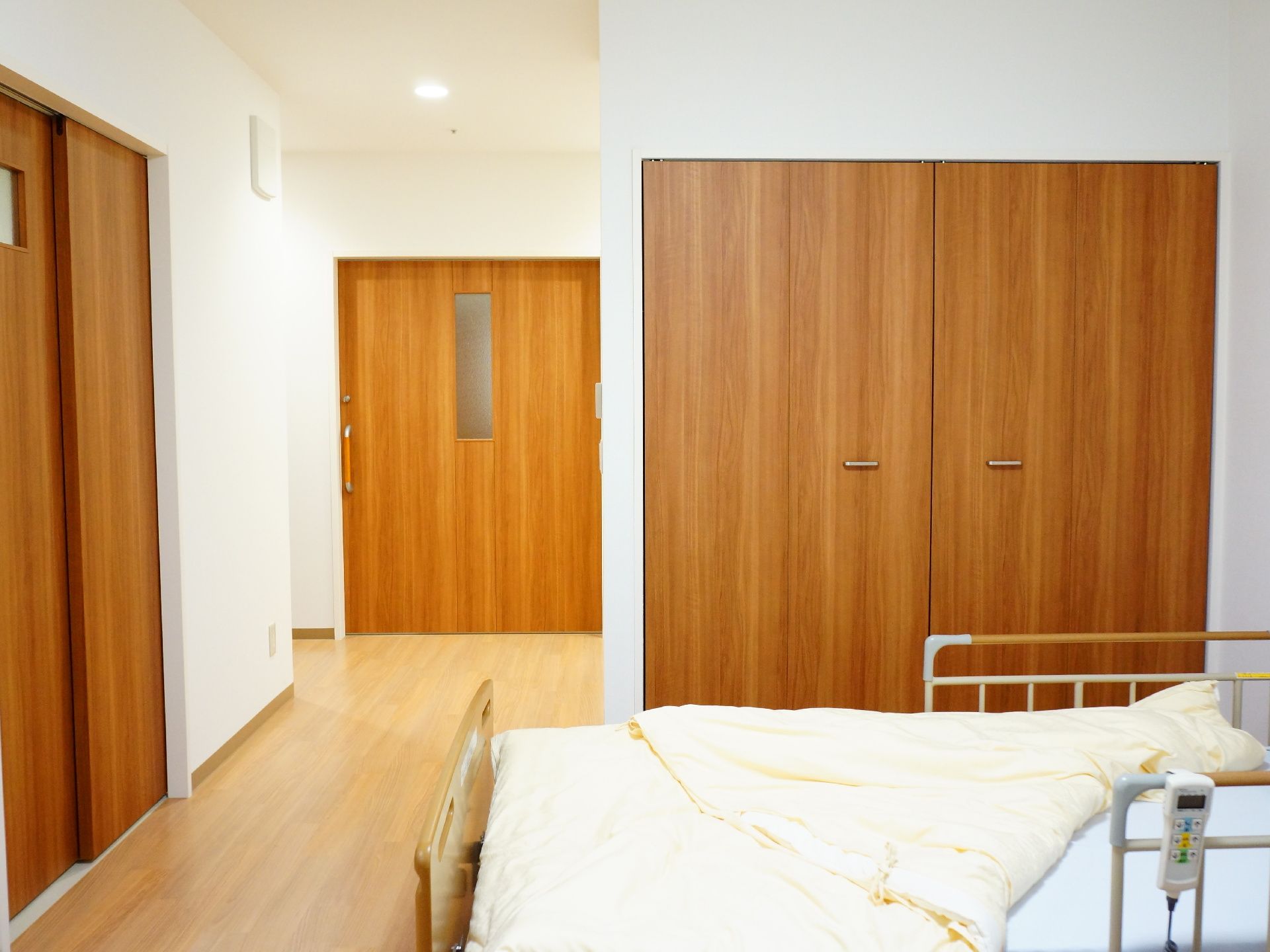 ベッドから入り口付近を見た写真。全体的にゆったりと余裕のあるつくりになっている。ドアは木目調で統一されており、目にも優しい仕様になっている。