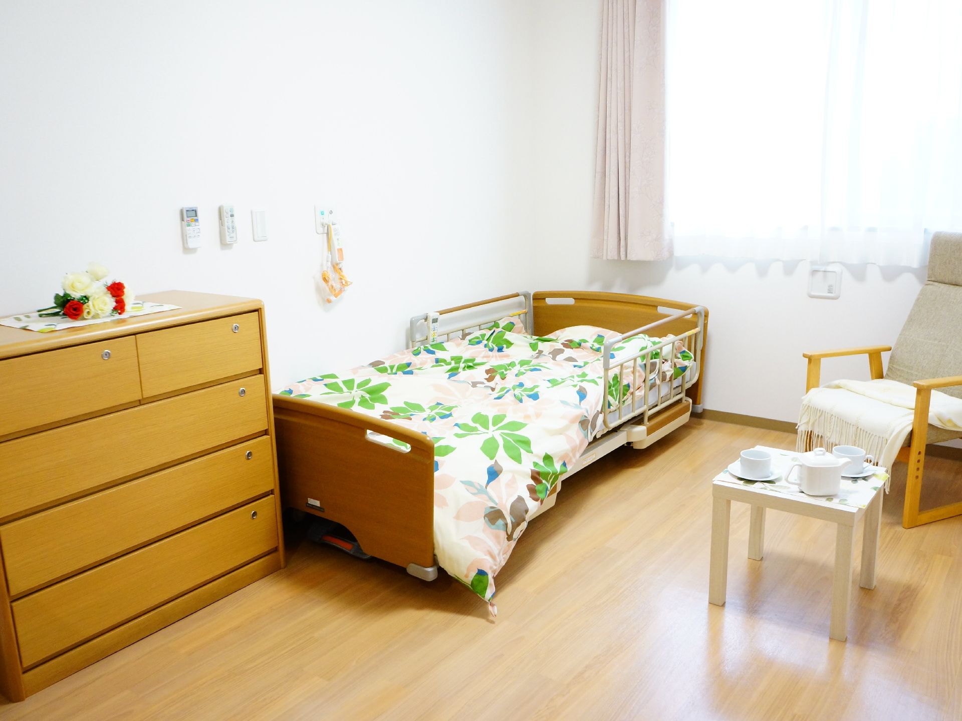 整理ダンスの上の花や机の上のティーセットなど、利用者が寛げるような空間ができている。座り良さそうなソファもあり、どこにいても安らげる居室。