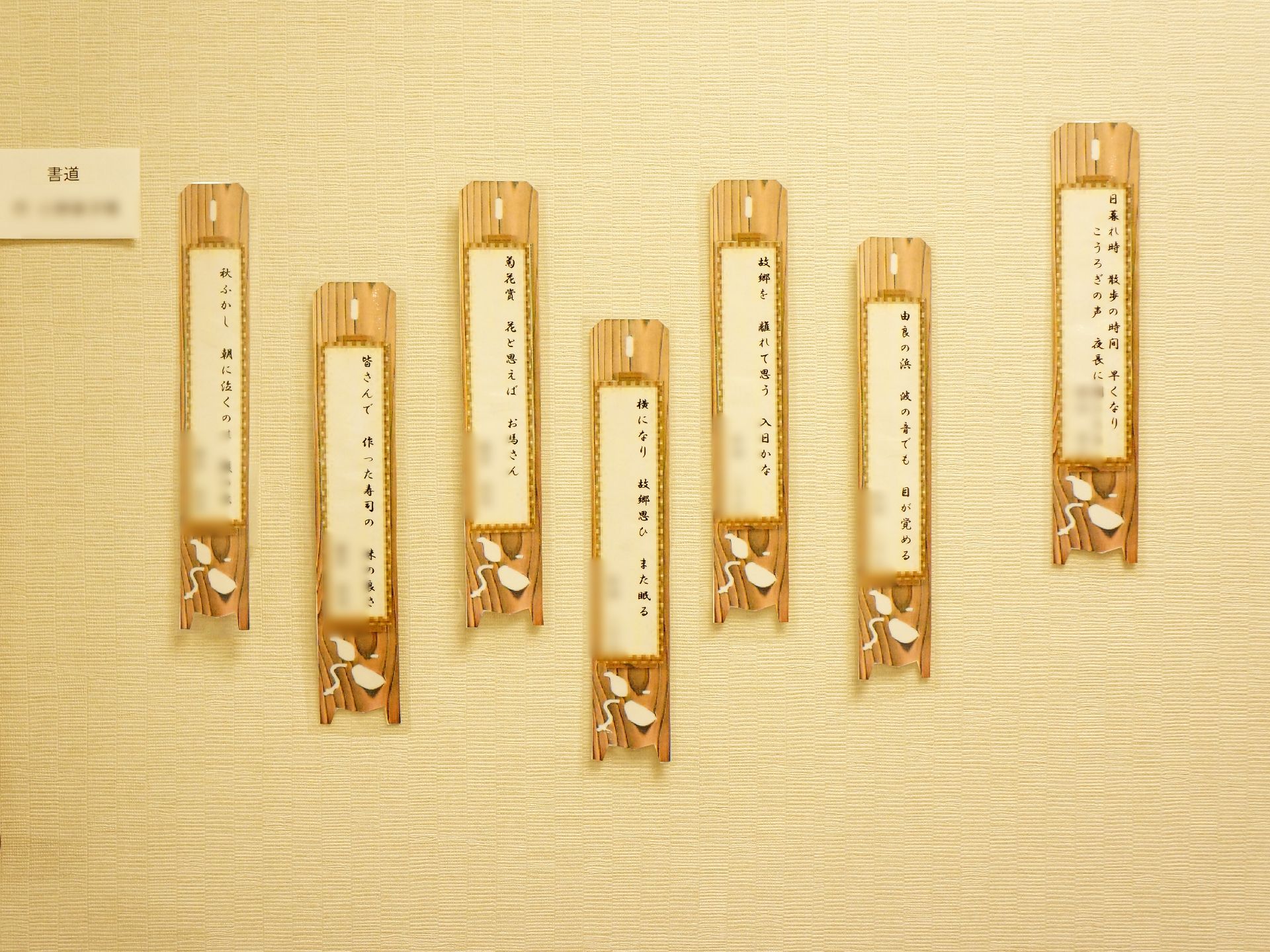 クリーム色の壁には額に入れられた俳句がかかっている。入居者達の作品であり、左側には書道の作品が額装されている。