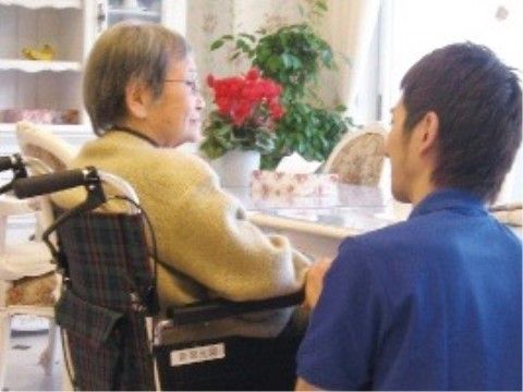 車いすに乗り窓の方向を見ている女性と話す男性スタッフ