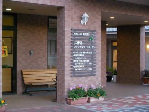 茶系のタイルでデザインされた玄関前の外観。施設の名称や提供している事業の内容を示したボードが掲げられている。