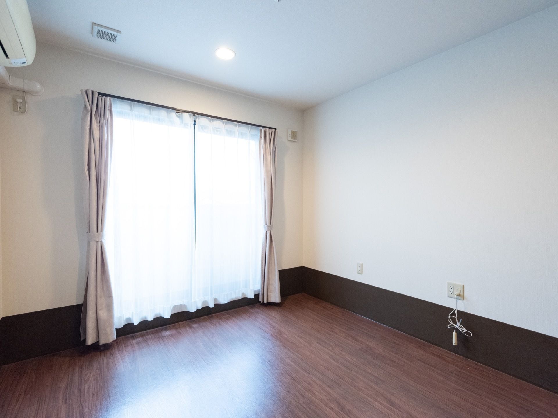 居室は空調完備となっている。床の色は濃い茶色で、白い壁と相まって落ち着いた雰囲気である。窓は大きく、日中は光が部屋に入る。