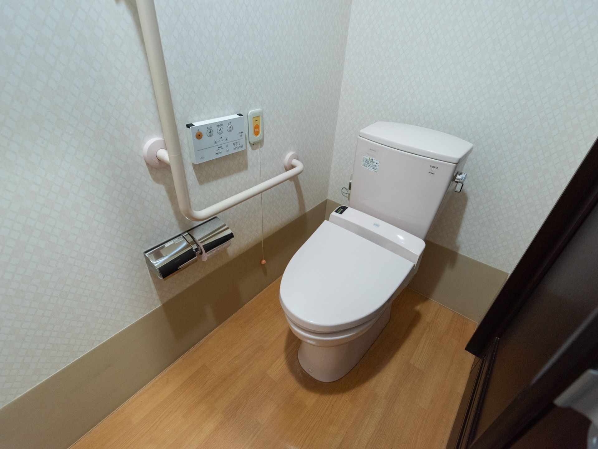 トイレの床には何も置かれておらずスッキリしている。壁には緊急コールと手すりが備わっており、安心して利用することができる。