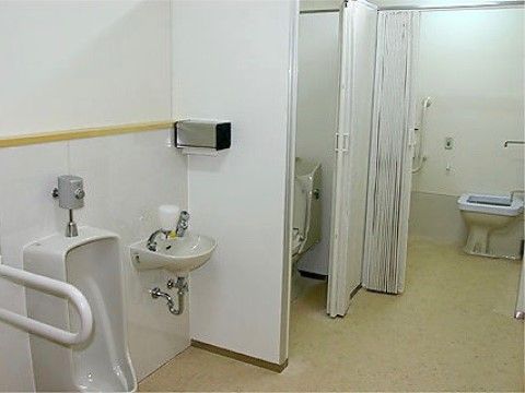 男性用小便器の横には、コンパクトな手洗い用の洗面ボウルがあり、液体ソープとペーパータオルが設置されている。