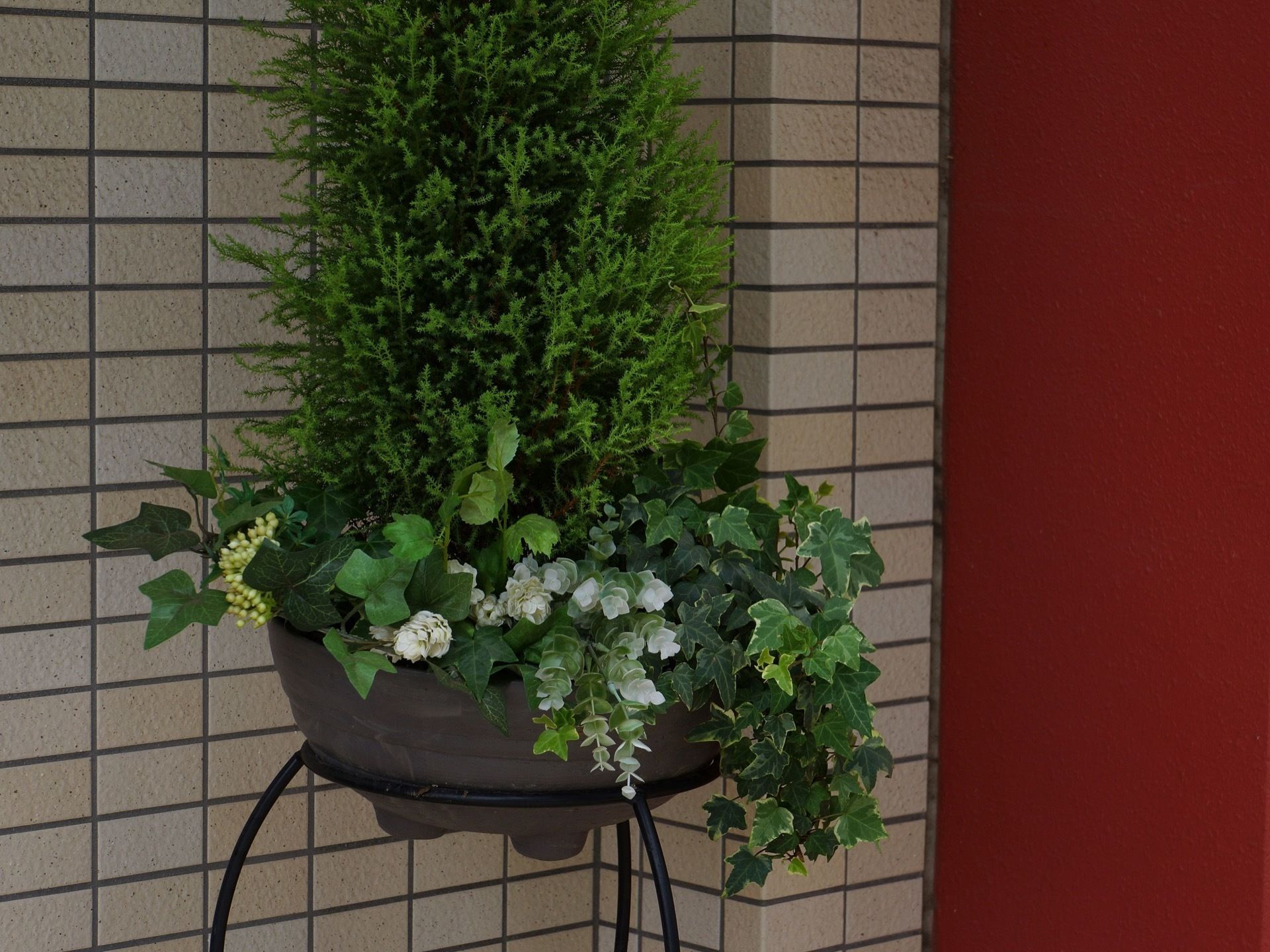 落ち着いた色の鉢に、ボリュームある植物や花が植えられている。エントランスに設置されており、さわやかな印象である。