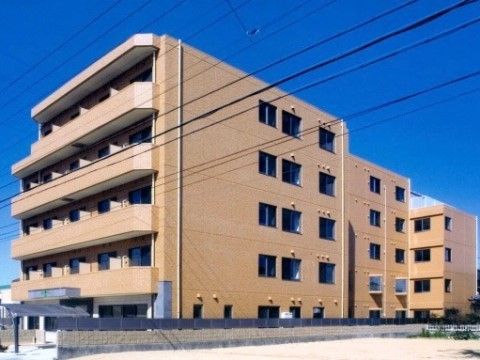 青空のもとに建つ、茶色に統一された外壁を持つ５階建ての建物