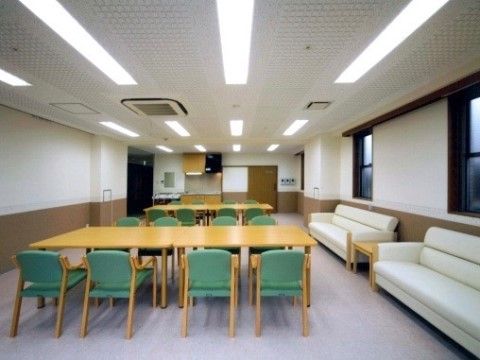 複数名が座れる白いソファーが設置してある。窓がある縦長の空間で、８名がけのテーブルセットを配置している。