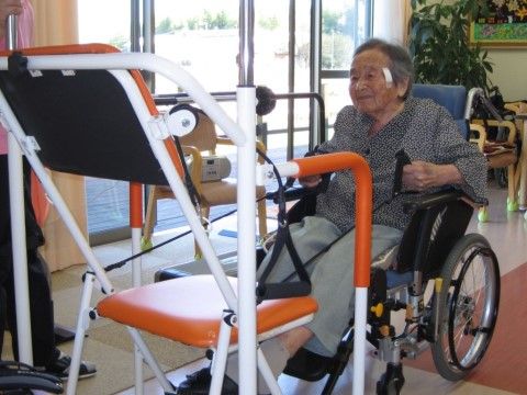 車椅子に乗った状態で、機器を使って上体のトレーニングを行う女性