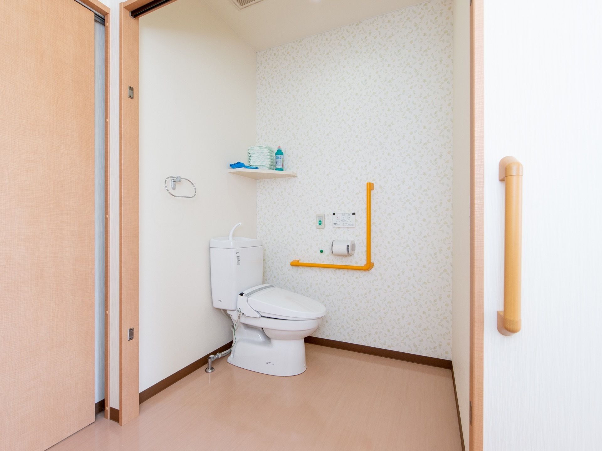 トイレへはフラットな床続きで移動ができる。温水洗浄便座器が完備され、壁には爽やかな柄のクロスが貼られている。