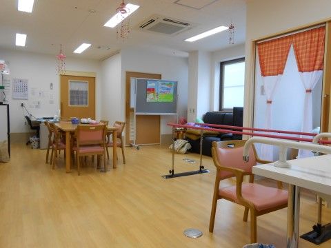歩行リハビリ用の手すりが置かれた、フローリング調の共有スペース
