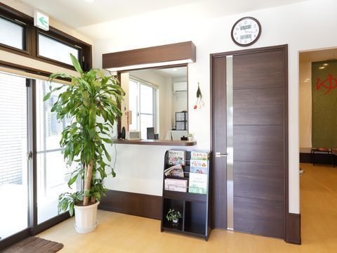 ドアのすぐ横に設置された、周囲にマガジンラックと観葉植物を置いたカウンター付きの事務所
