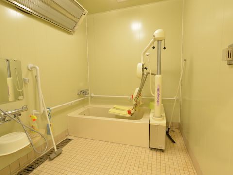座位入浴が出来るリフトを備えた浴室は、リフトを動かしたり一緒に介護士が入ったり出来るように洗い場が広くなっている。手すりもあり安心である。