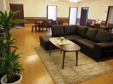 ソファー席とテーブル席が置かれたフローリング調の床を持つ広い部屋