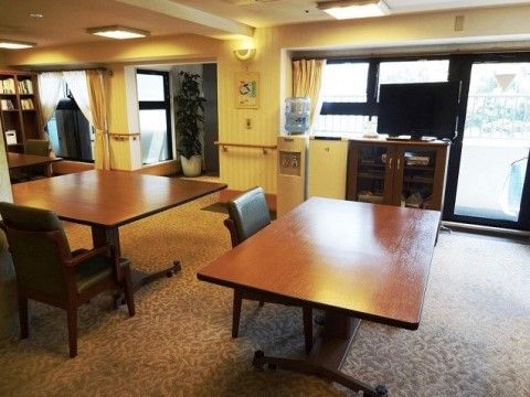 施設内に設けられた食堂には、大きな長方形の机が２つ並べられている。窓際には、テレビが設置されている。