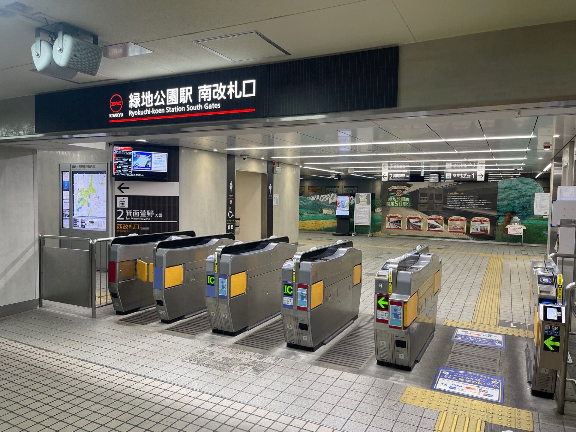 施設から徒歩の場所には駅があり、改札口の上には駅名の書かれた青い看板が設置されている。左側には、コインロッカーが用意されている。