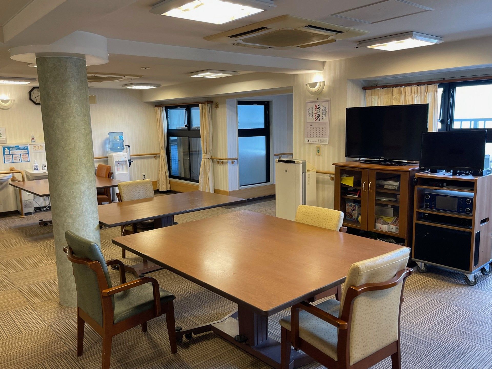 施設内に設けられた食堂には、大きな長方形の机が２つ並べられている。窓際には、テレビが設置されている。