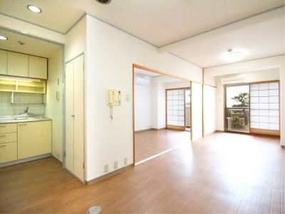 居室の床はフローリングになっており、広いスペースが確保されている。壁と天井の色は白色系で、キッチンが設置されている。