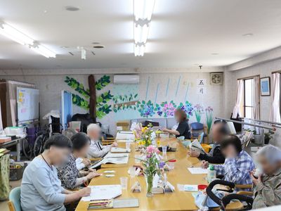 共有スペースの中央にテーブルを寄せて配置している。入居者様が集い作業を行ったり、新聞を読んだり、思い思いに過ごされている。