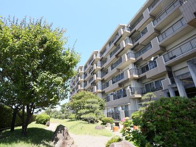 施設に併設された日本庭園。建物外観はベージュと白を基調とした落ち着いた色合いである。施設の部屋には全てベランダが設置されている。