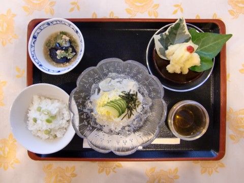 茶色の縁の黒いお盆の上に食事がのっている。一品ずつ食器が分けられており、それぞれ違うデザインの器である。